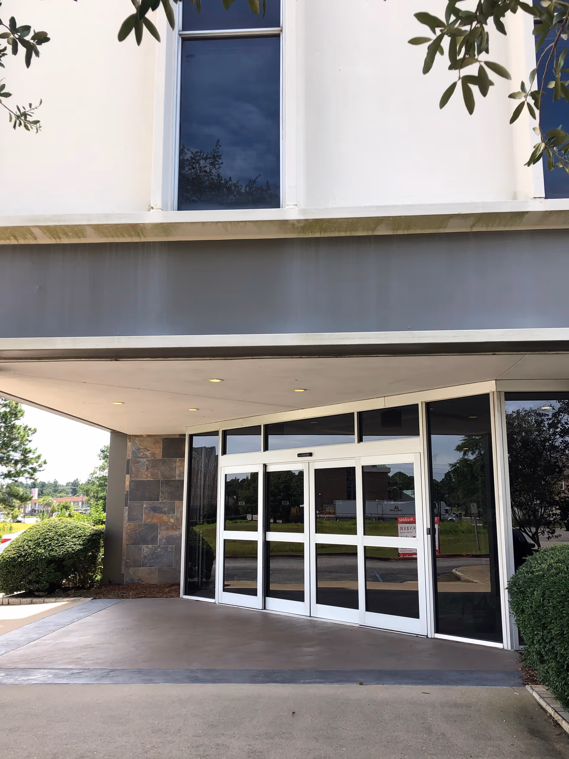 Exterior view of a modern senior living facility entrance with glass doors.