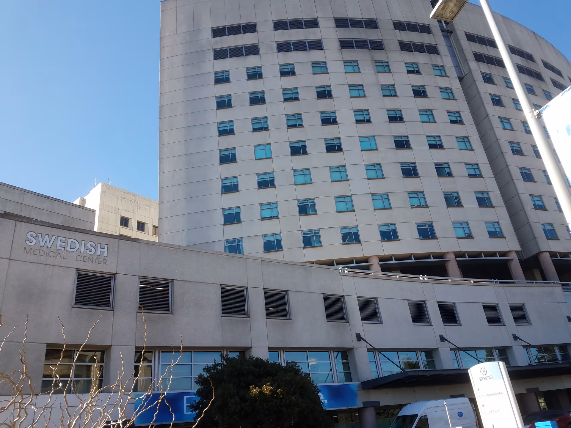 Tall hospital building exterior with Swedish Medical Center signage against a clear blue sky.