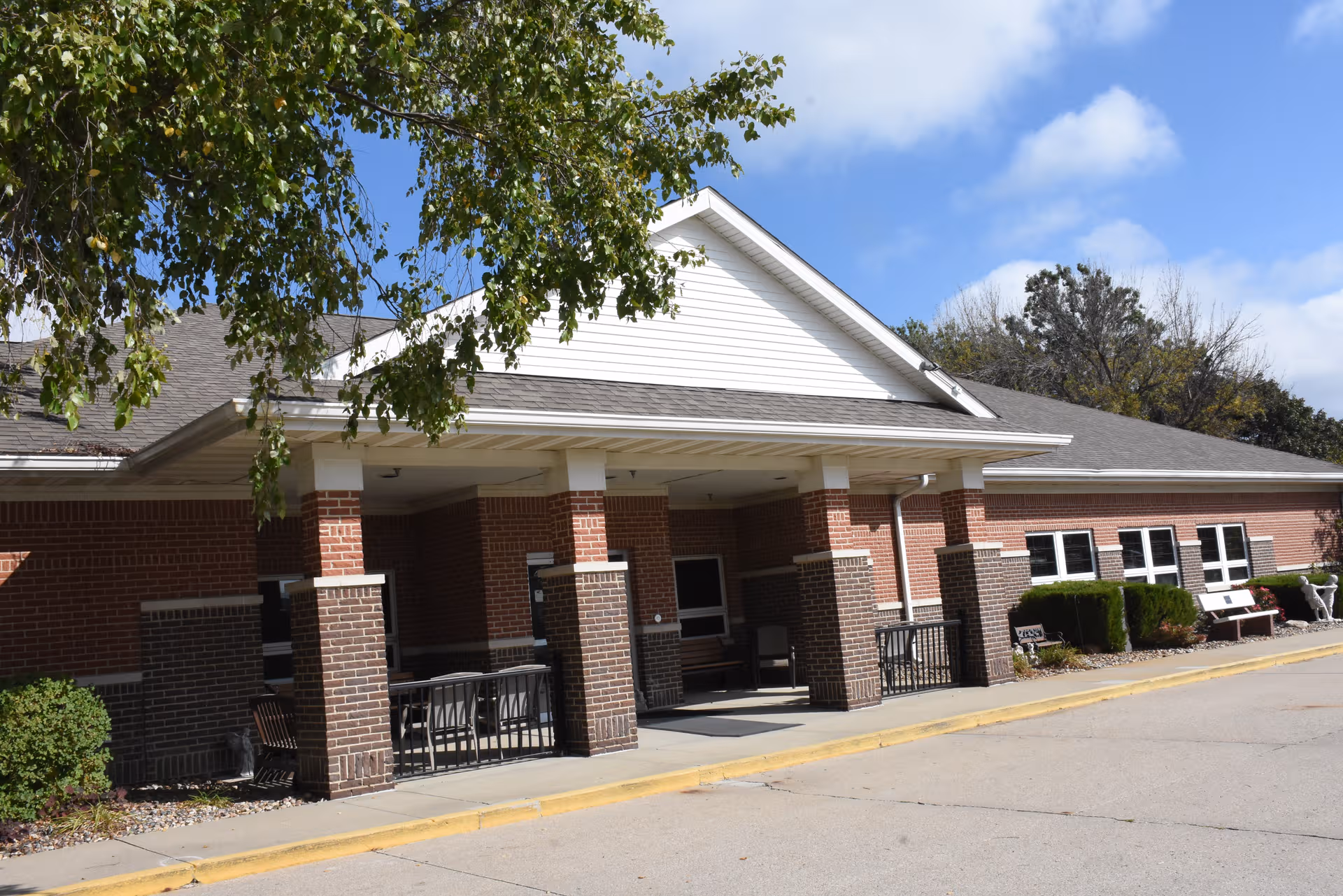 Brick senior living facility with a covered entrance and a row of windows along the front.