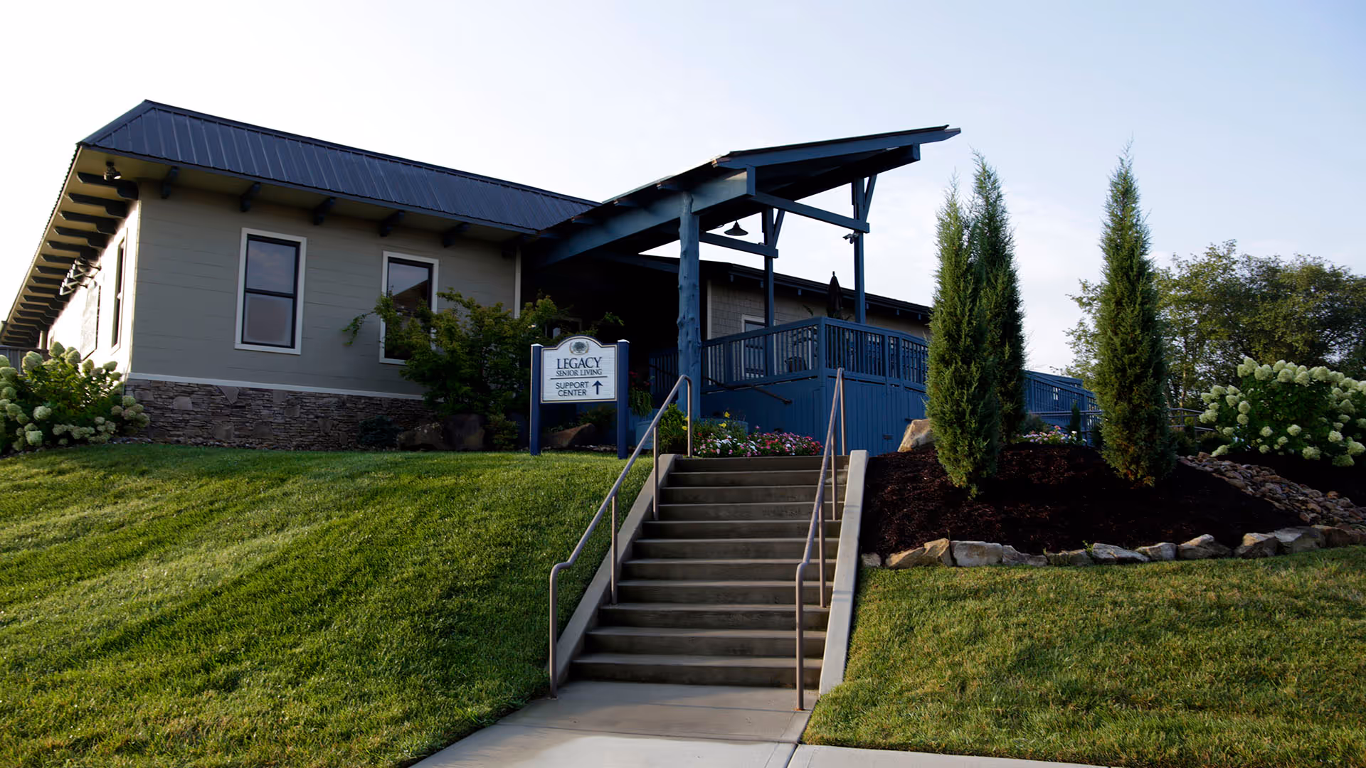 Front view of Legacy Senior Living Support Center with stairs, covered entry, and landscaped lawn.