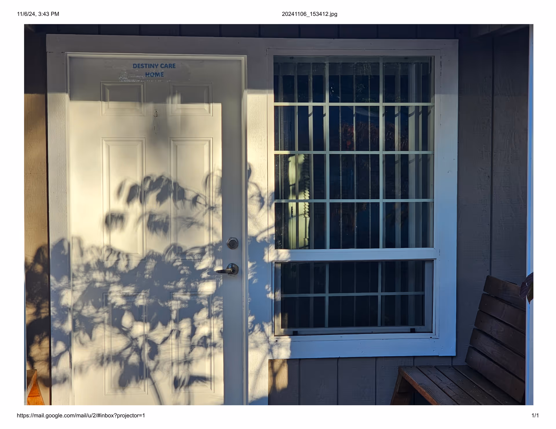 Front entrance of Destiny Care Home with a window and wooden bench outside.