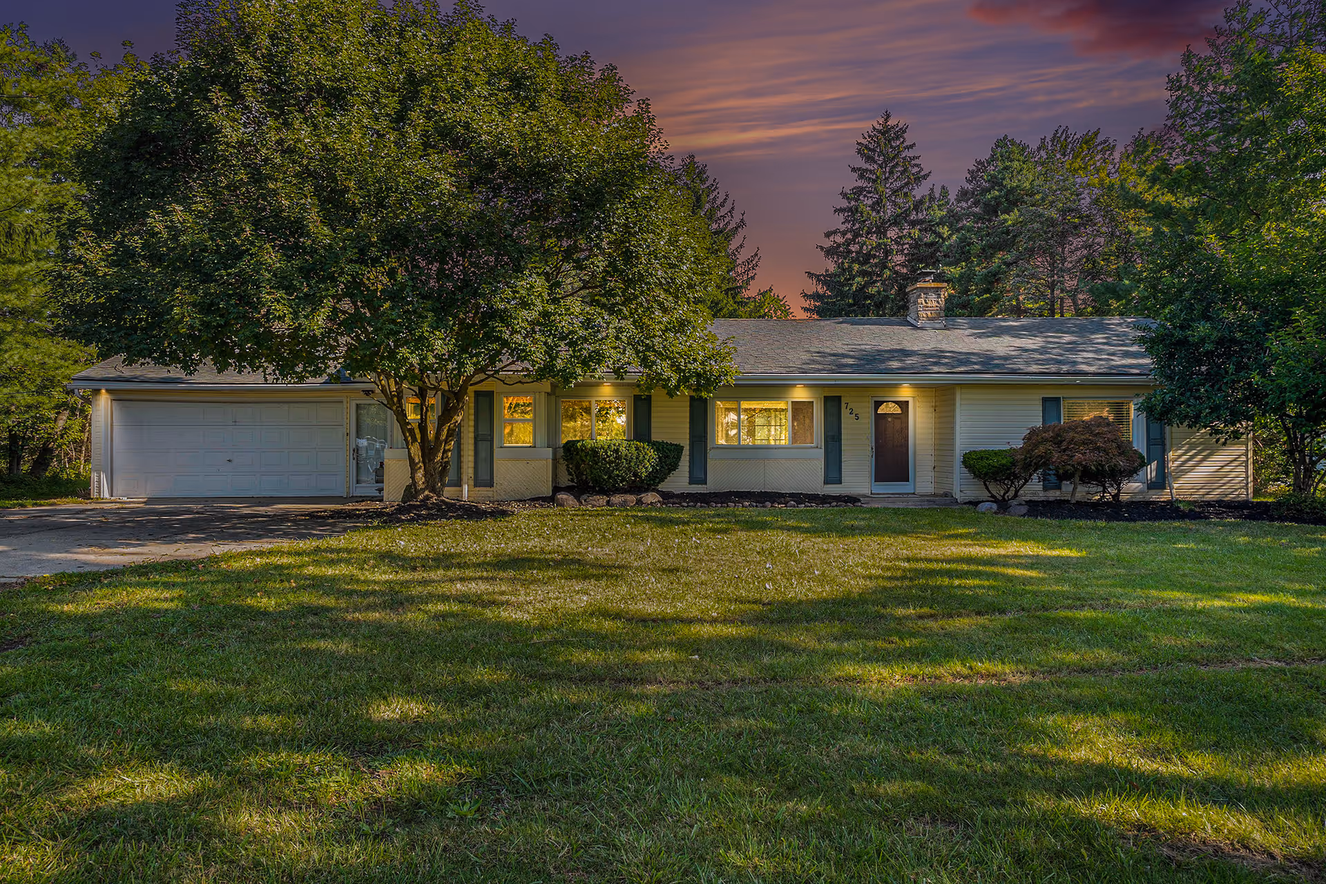 Single-story senior living facility front with a garage, lawn, and trees.