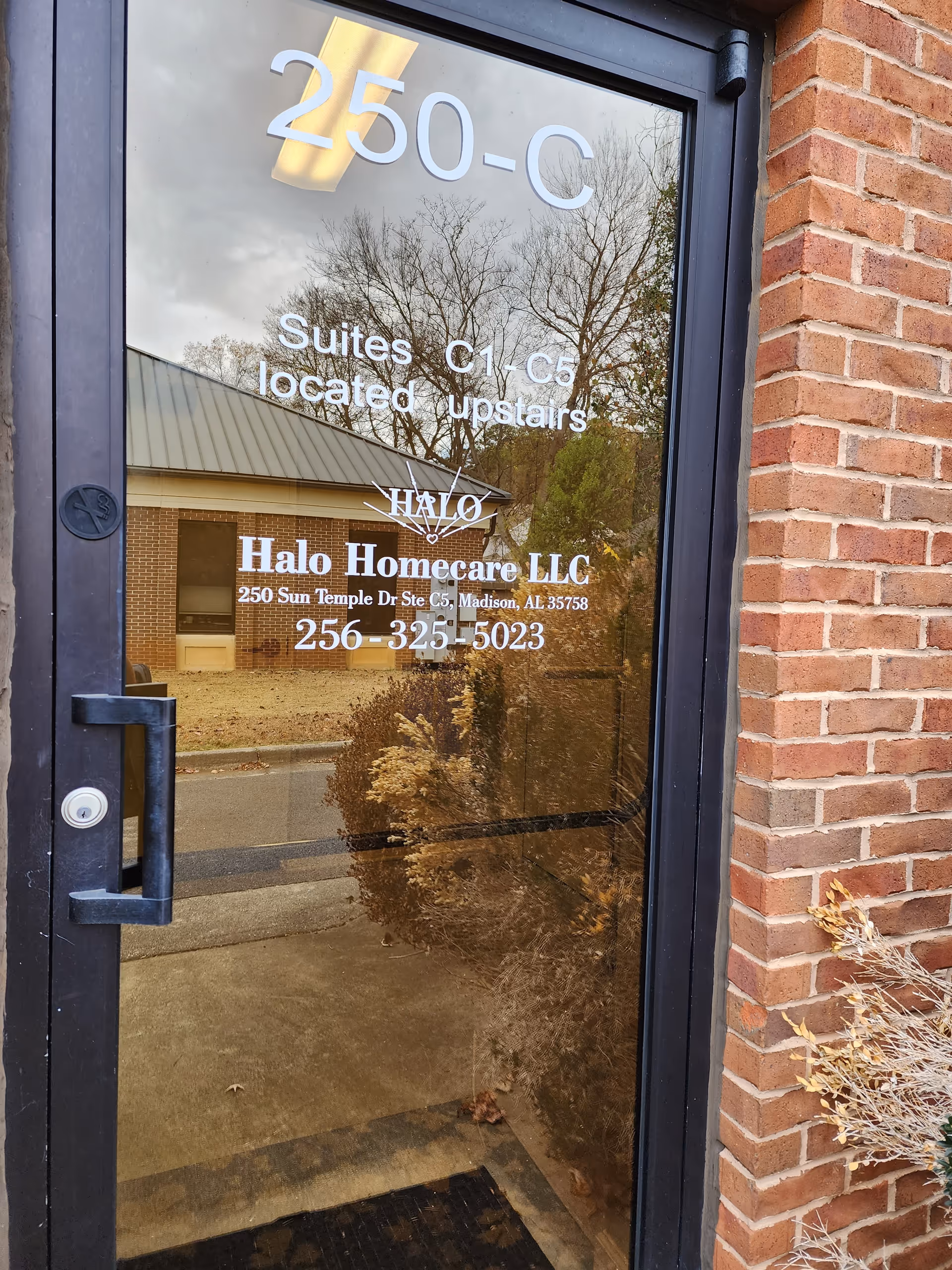 Glass door entrance with Halo Homecare LLC sign, brick exterior, and reflected outdoor scene.