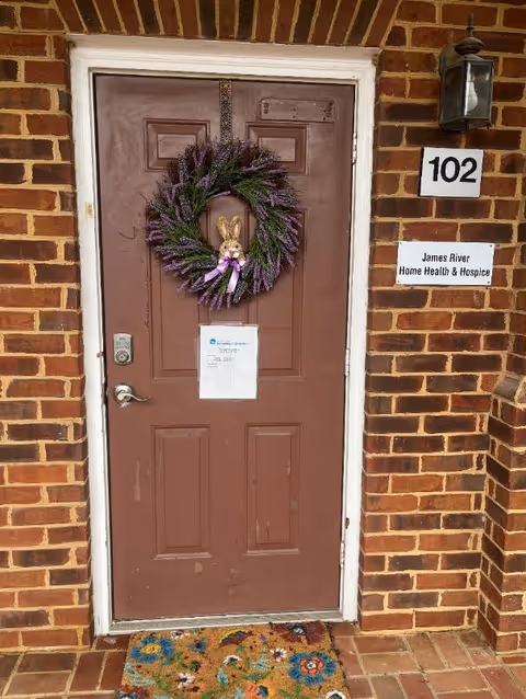 Brown front door with wreath on brick exterior and James River Home Health & Hospice sign.