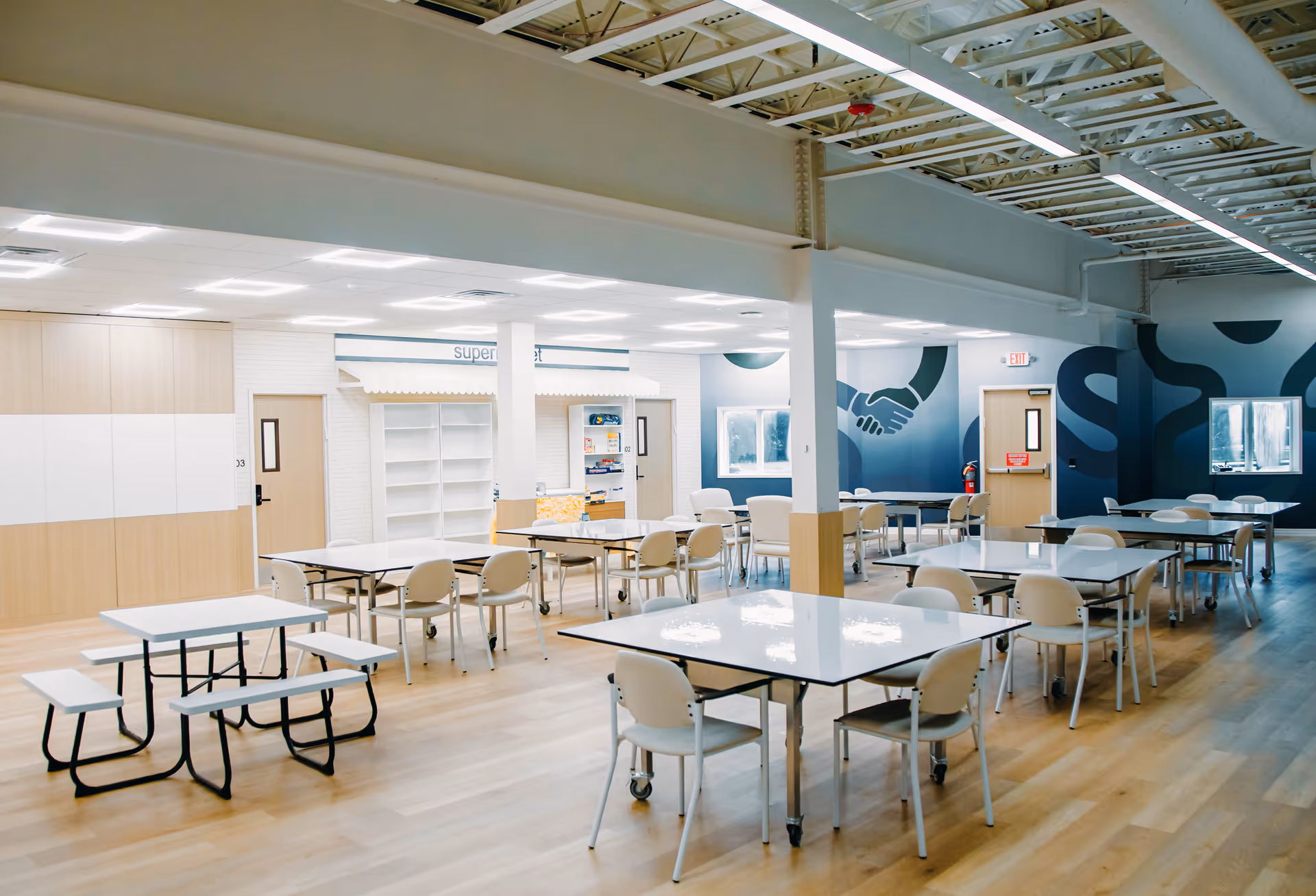 Spacious communal dining area with tables and chairs in a modern, well-lit facility.