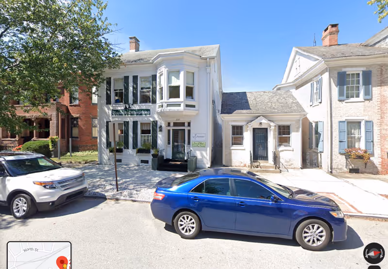 Exterior view of a row of buildings with parked cars along the street.