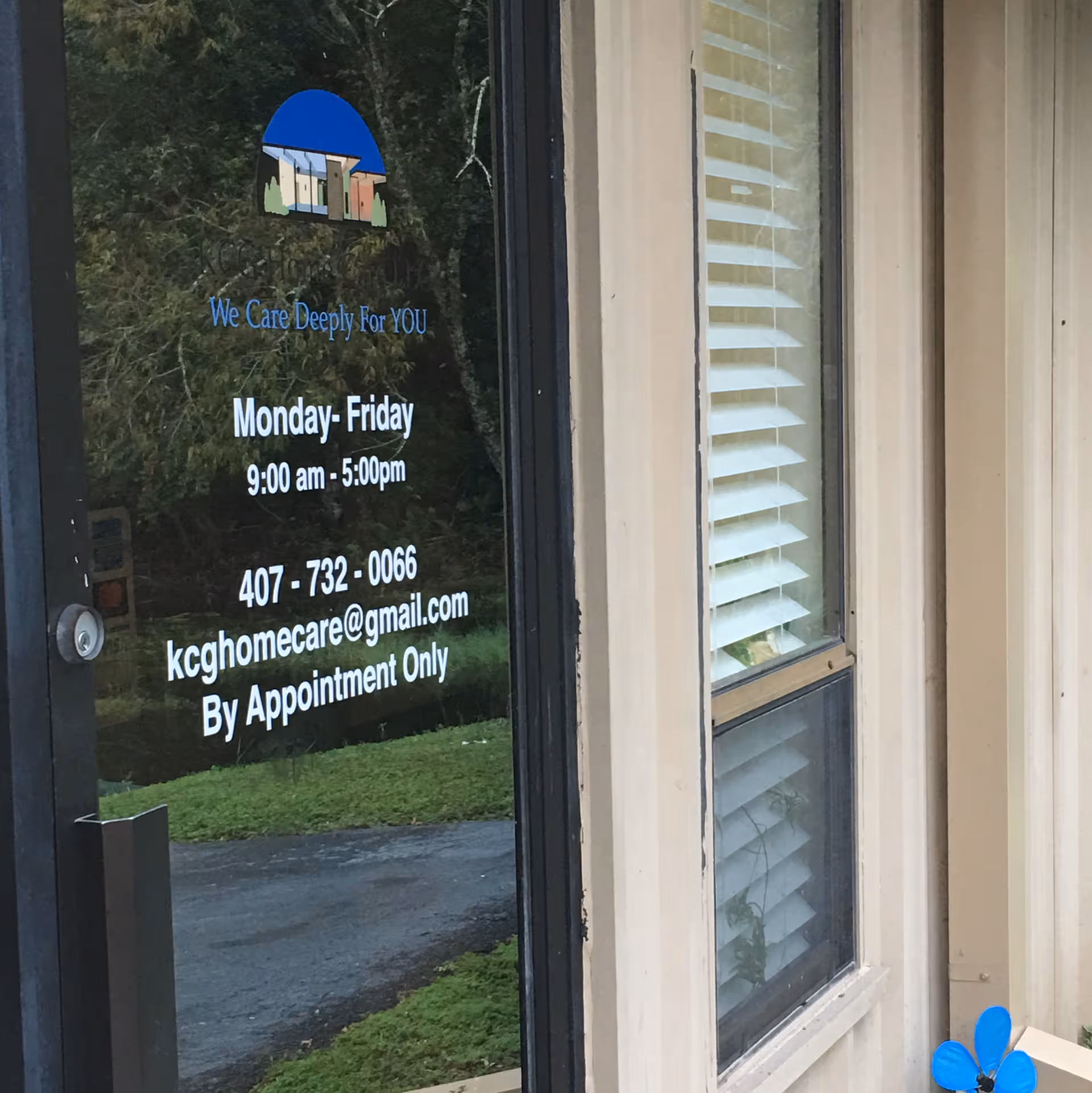 Front glass door displays Congenial Home Health Care logo and hours, with greenery reflected outside.