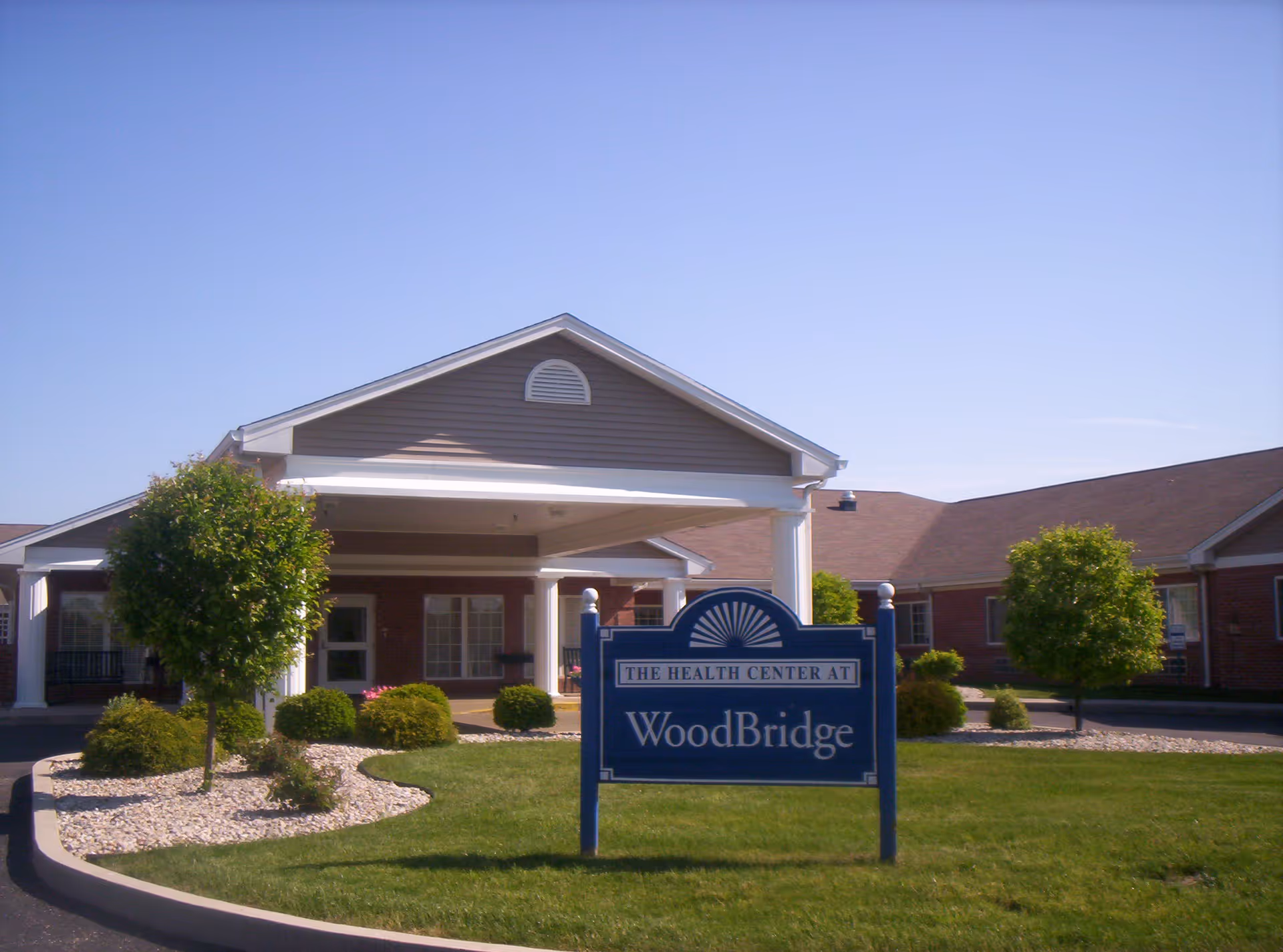 Front exterior of WoodBridge Health Campus with entrance, sign, and landscaped lawn.