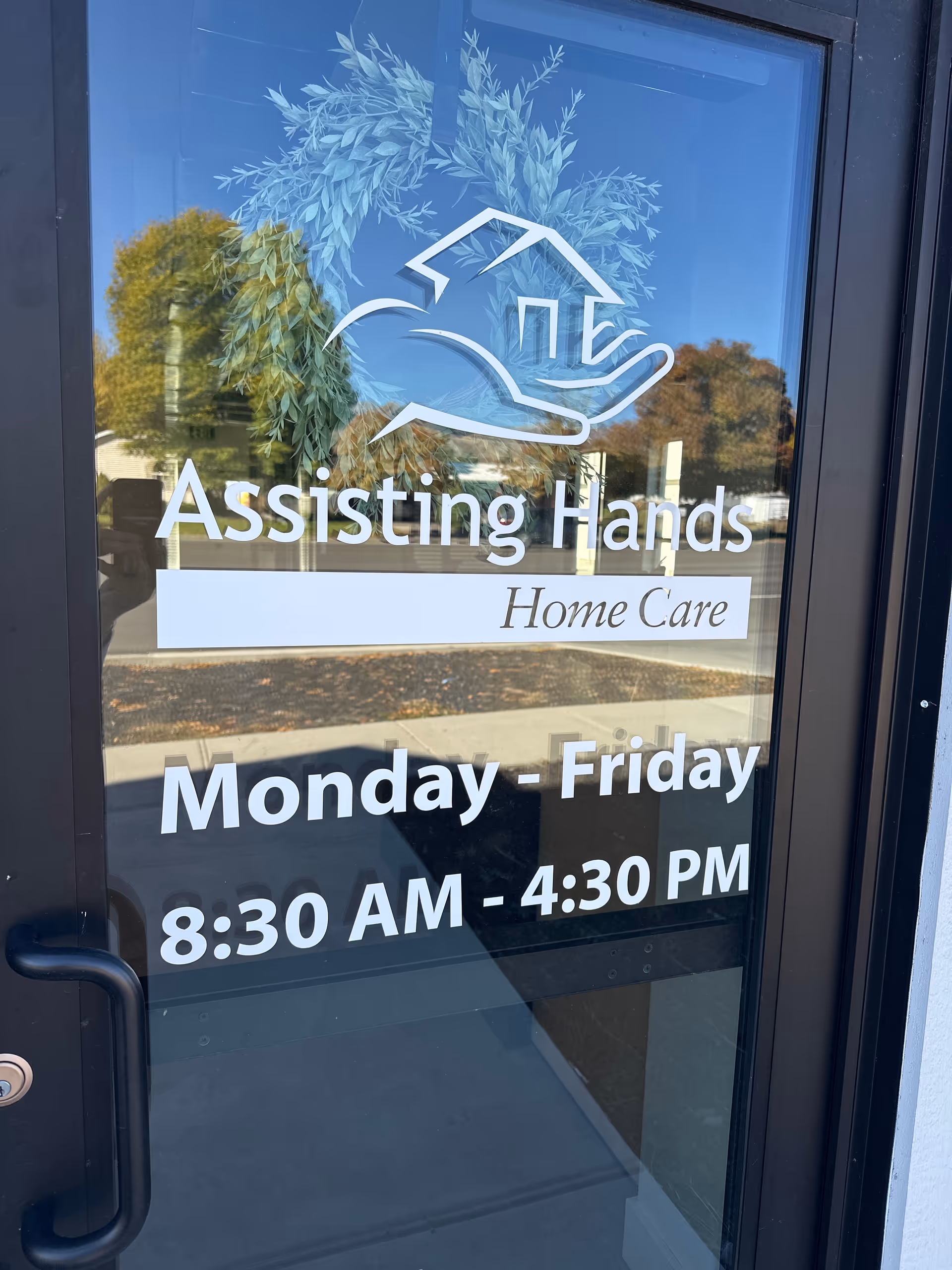 Glass entrance door with Assisting Hands Home Care logo and hours 8:30 AM to 4:30 PM.