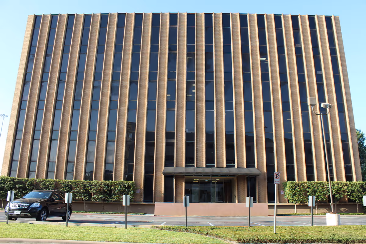 Tall brick office building with vertical window columns and a glass entrance.
