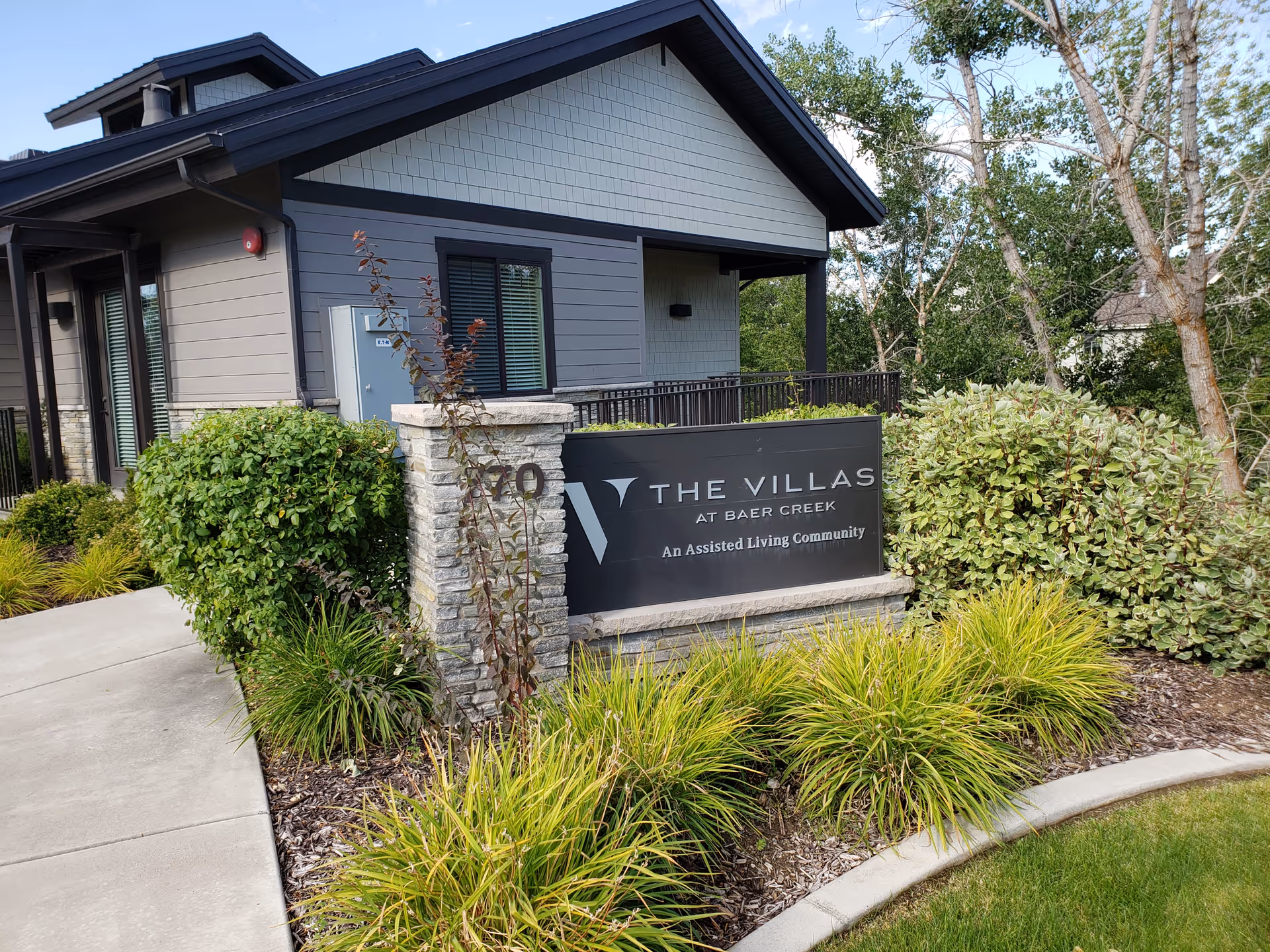 Exterior view of The Villas at Baer Creek with entrance sign and shrubs.