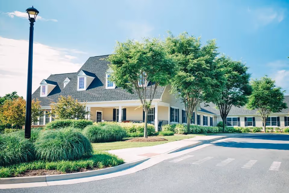 Single-story senior living facility with manicured landscaping and a driveway at the front.