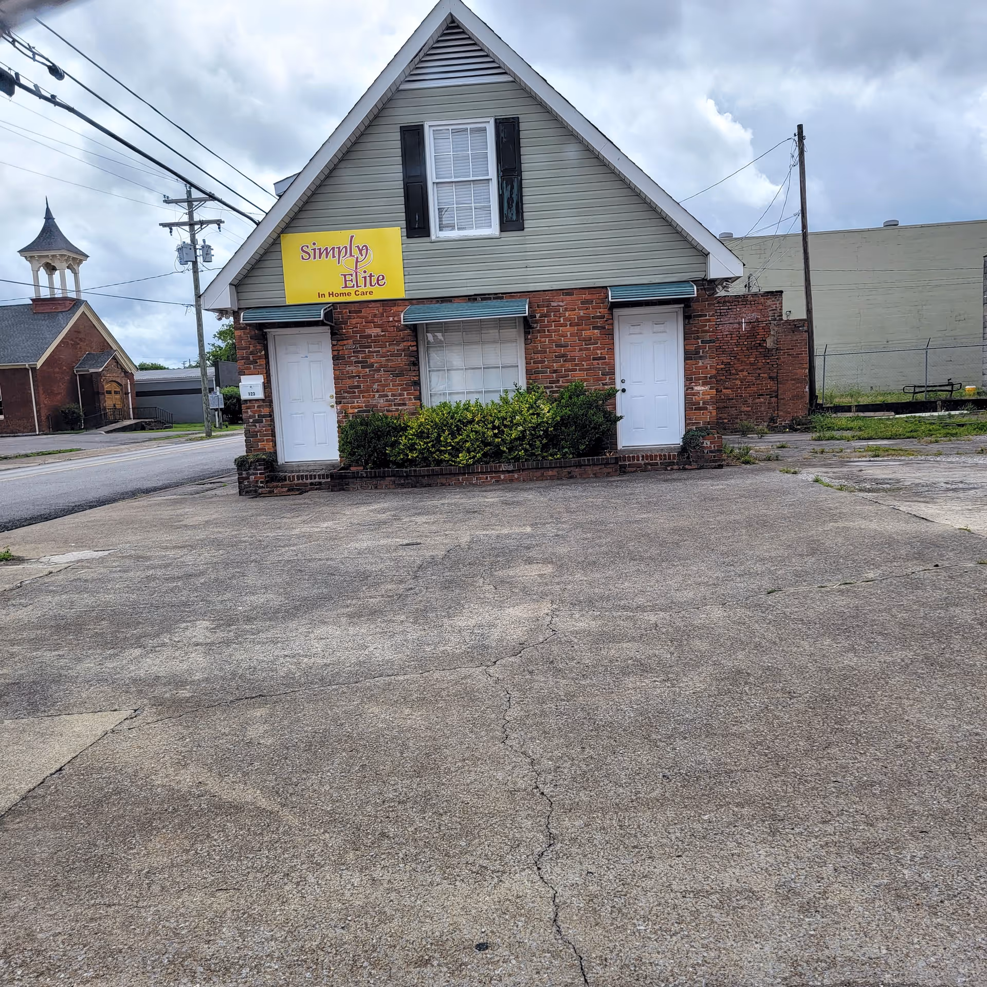 Small brick building with two white doors and a yellow sign.