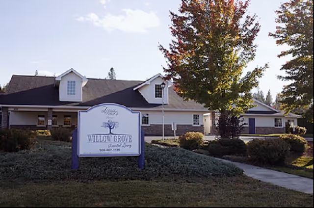 Exterior view of Willow Grove senior living facility with sign and landscaped entrance.