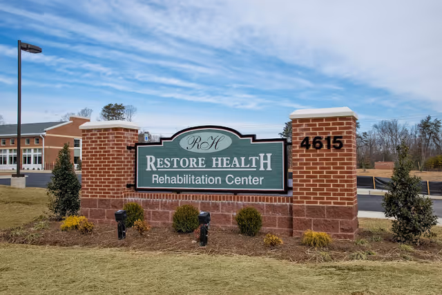 Brick entrance sign reading 'Restore Health Rehabilitation Center' with address 4615 and the facility building visible behind it.