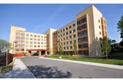 A multi-story beige building for Rebekah Rehab Extended Care Center with a wide driveway.