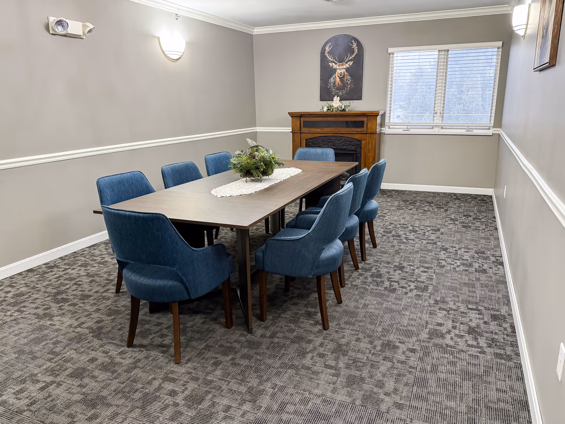 A long dining table with blue upholstered chairs in a well-lit dining room.