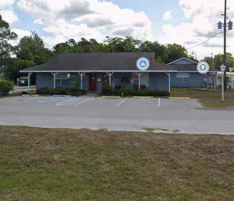 Front view of a single-story blue building with a parking lot.