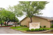 Exterior view of Southwood Care Center with a sign, trees, and landscaped grounds.