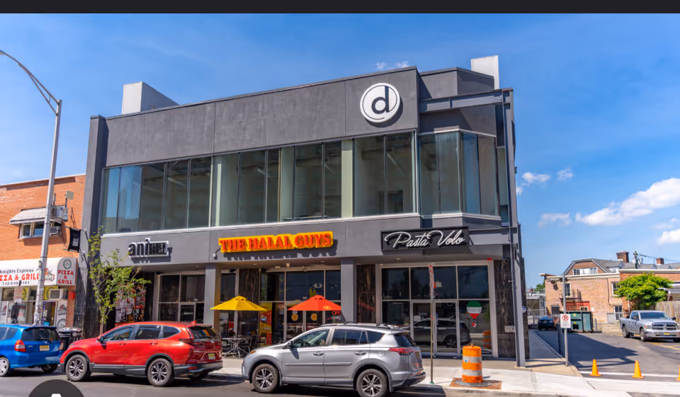 Two-story building facade featuring The Halal Guys storefront and outdoor seating.