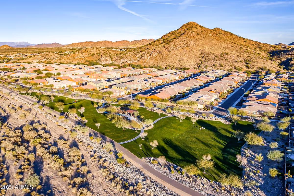 Aerial view of a desert senior living campus with beige homes and green open spaces.