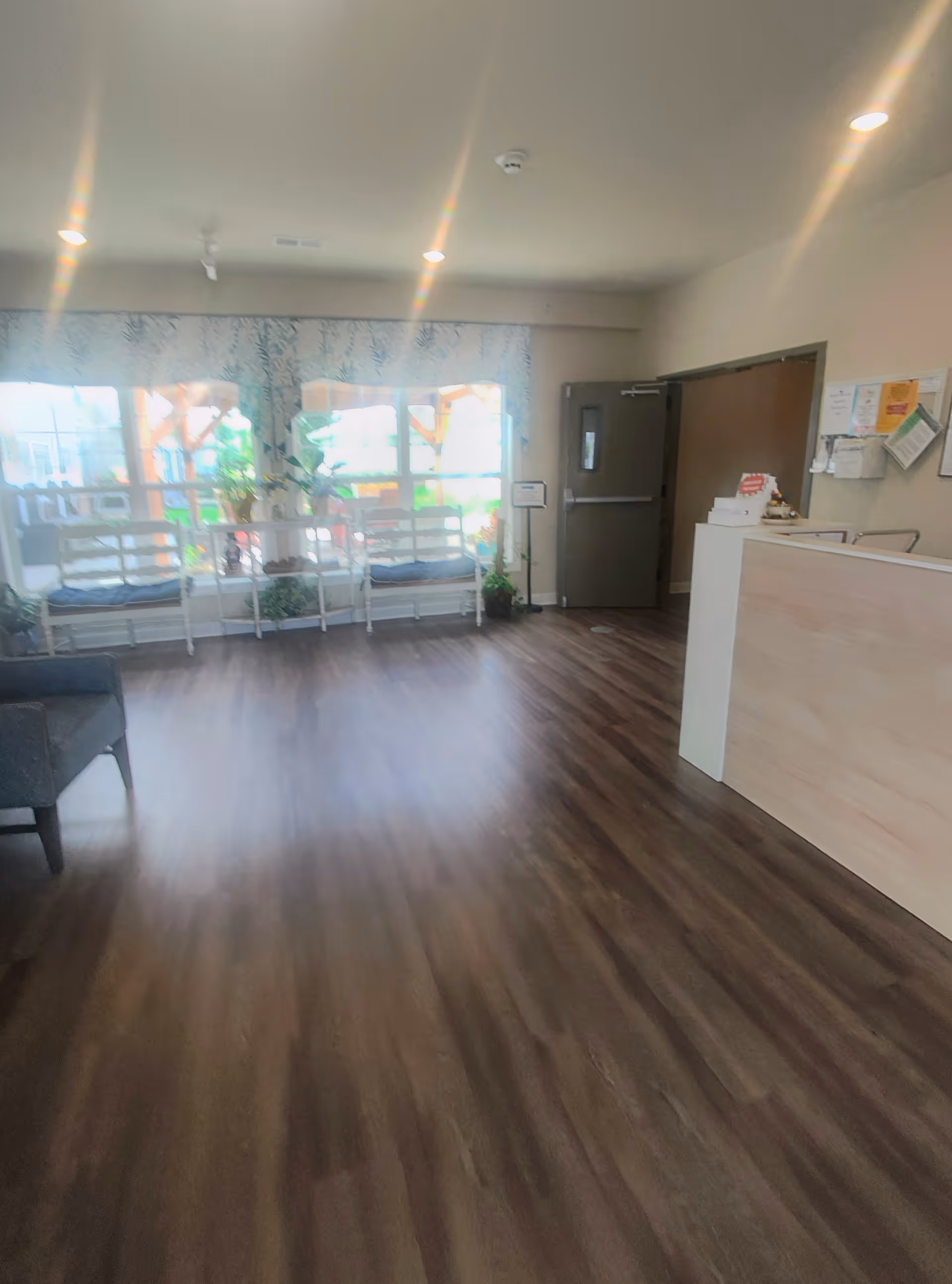 Bright interior senior living lobby with seating, plants, and a reception desk.
