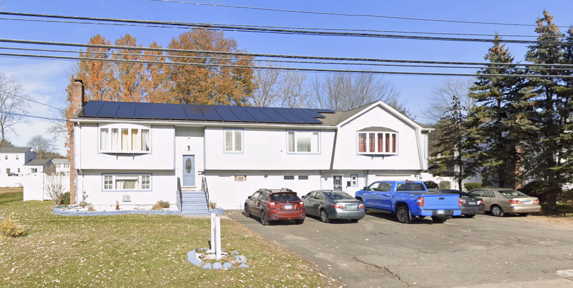 Exterior view of a two-story senior living facility with solar panels and parked cars.