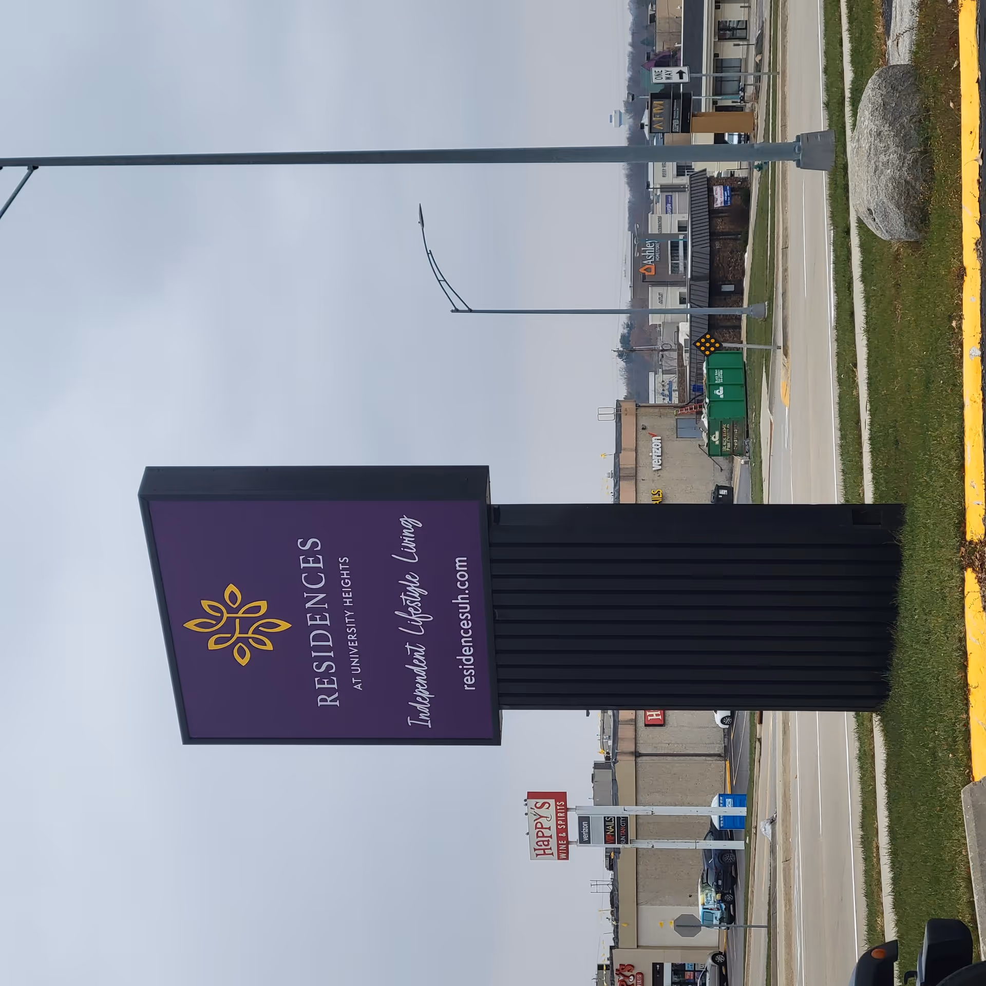 Large purple sign for Residence at University Heights outside near a road.