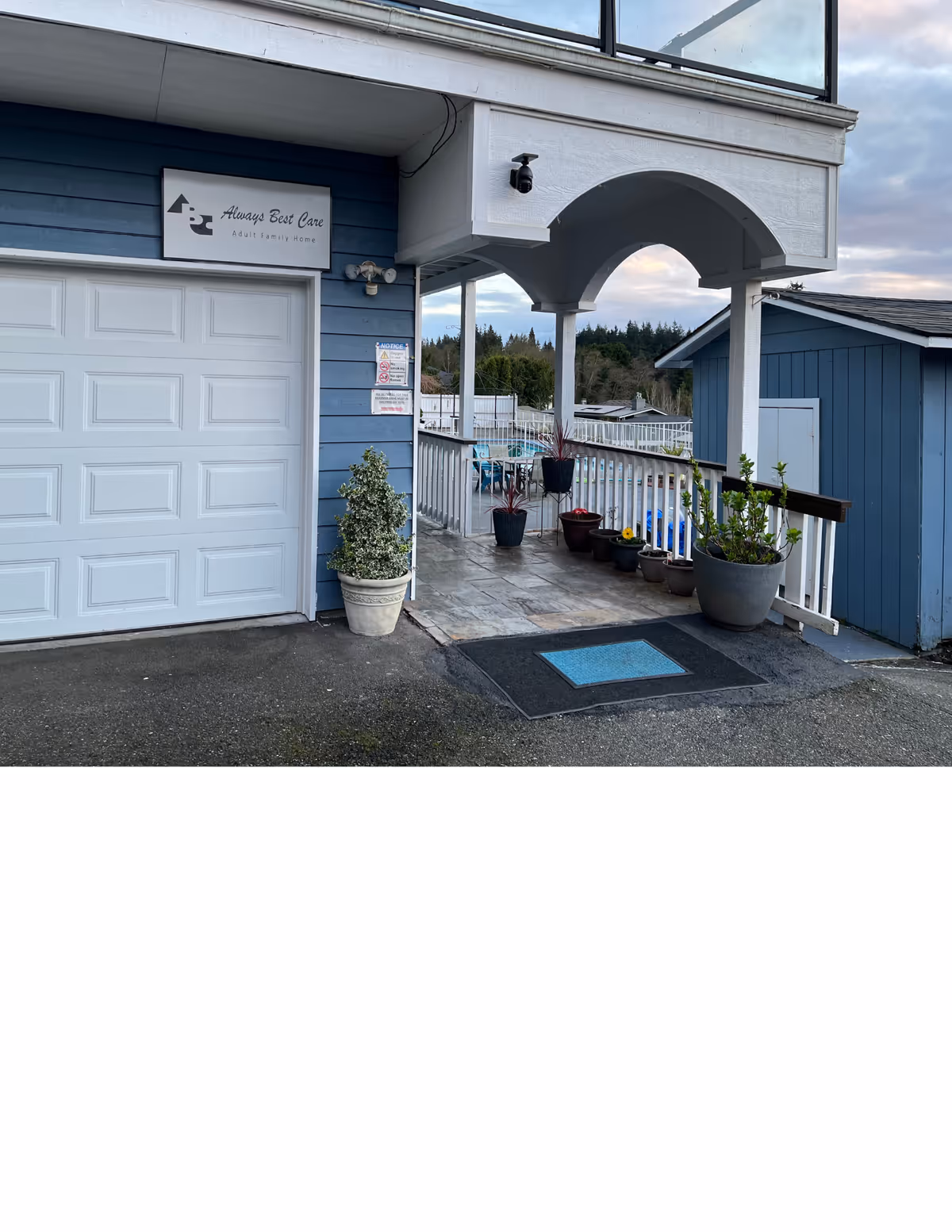 Blue exterior of Amazing Grace AFH II with arched porch and potted plants.