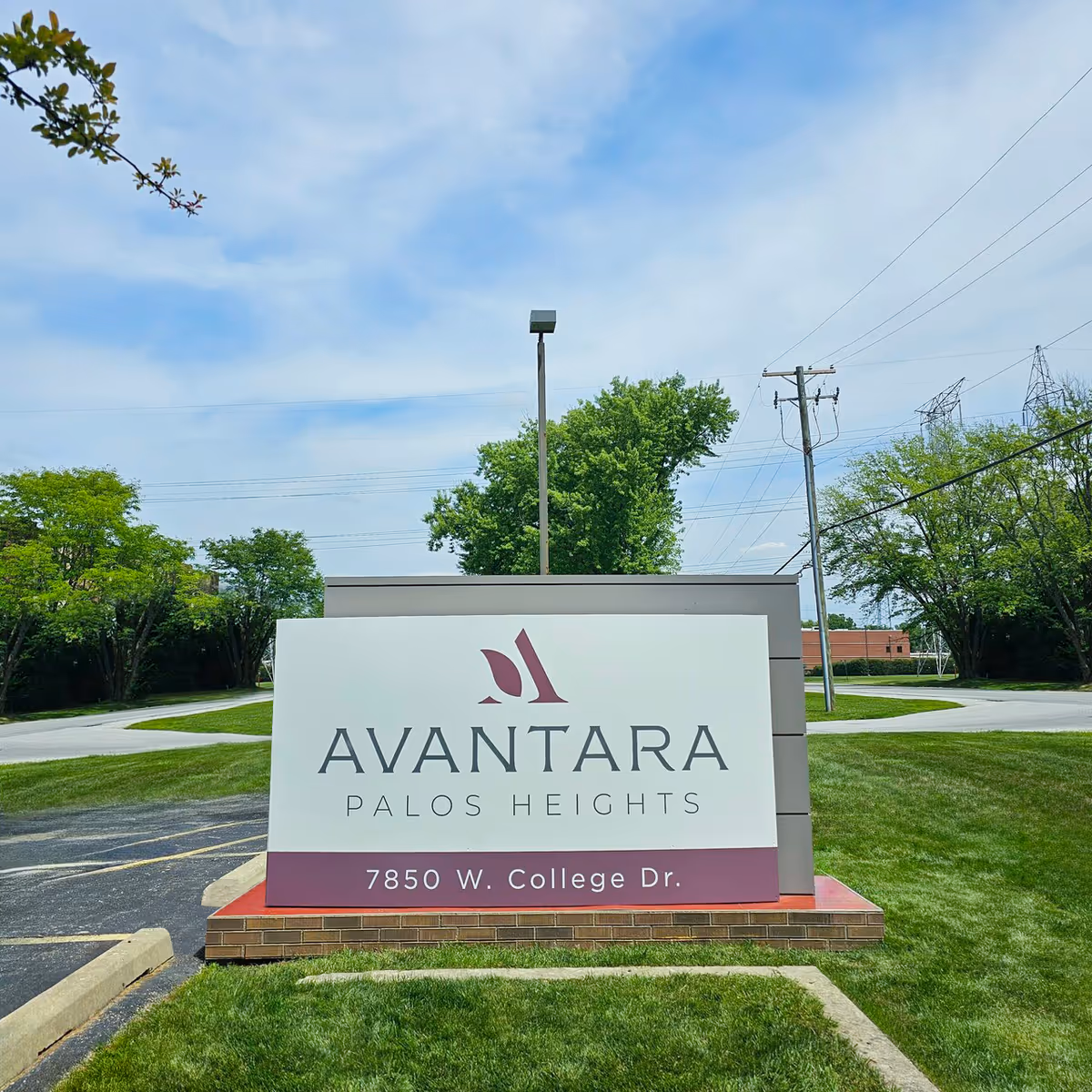 Exterior sign for Avantara Palos Heights on a grassy landscape near the road.