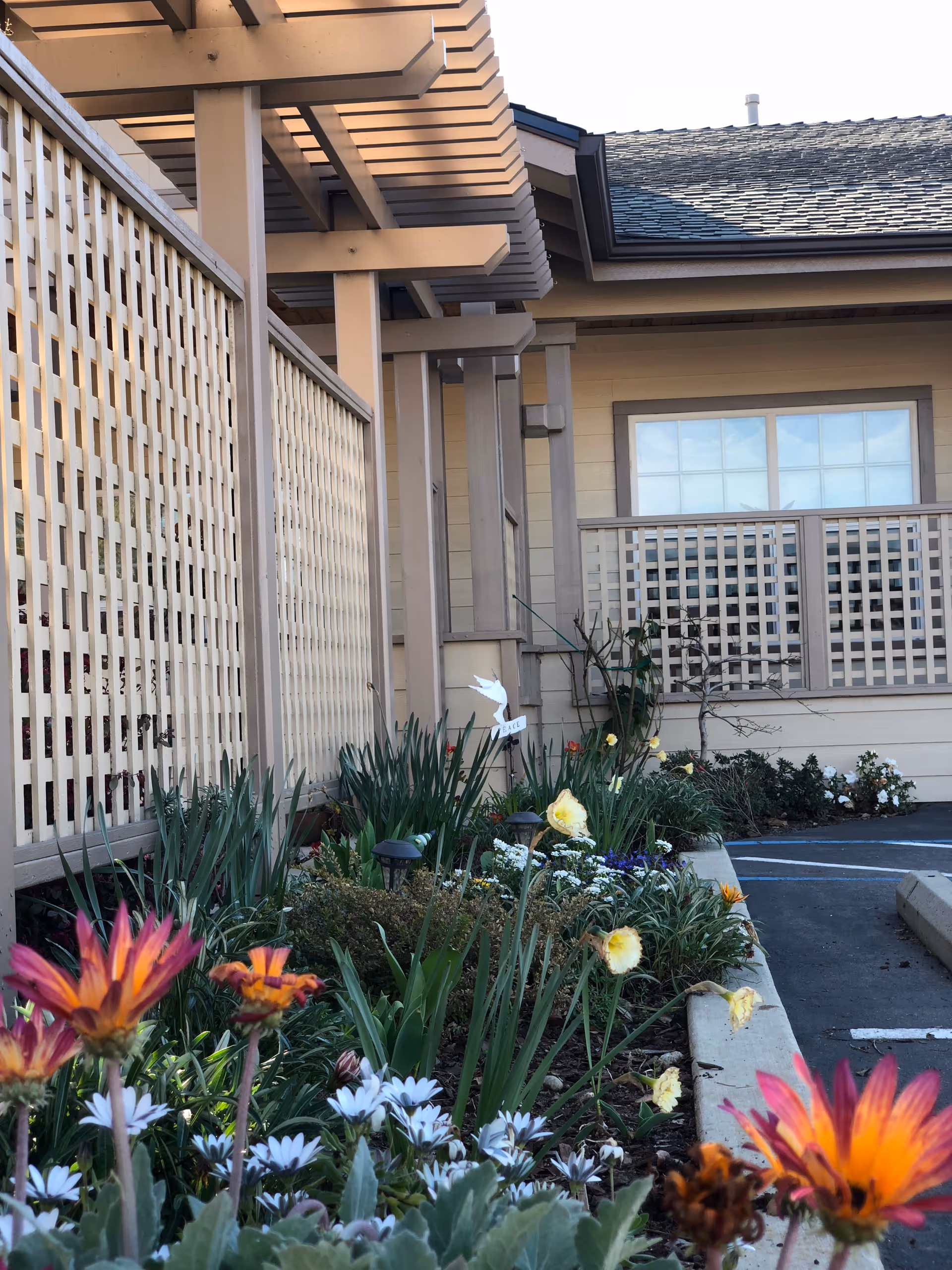 Exterior view of Roseberry Care with lattice fences and blooming garden flowers.