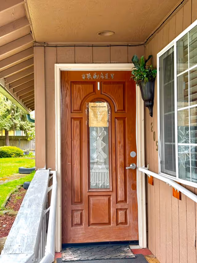 Exterior entry door of Apple Tree Adult Family Home with decorative glass and potted plant