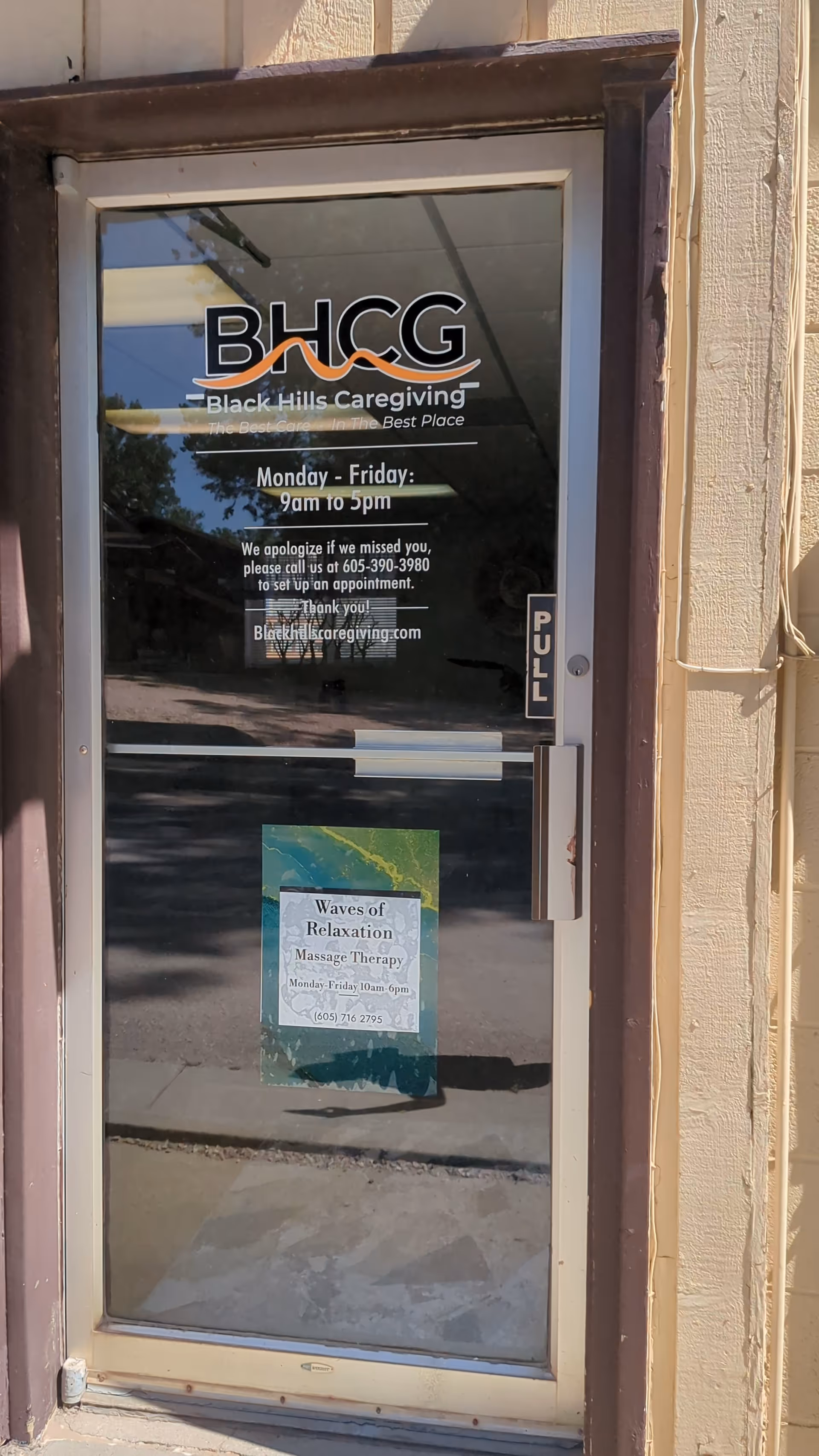 Glass entrance door for Black Hills Caregiving with BHCG logo and hours.
