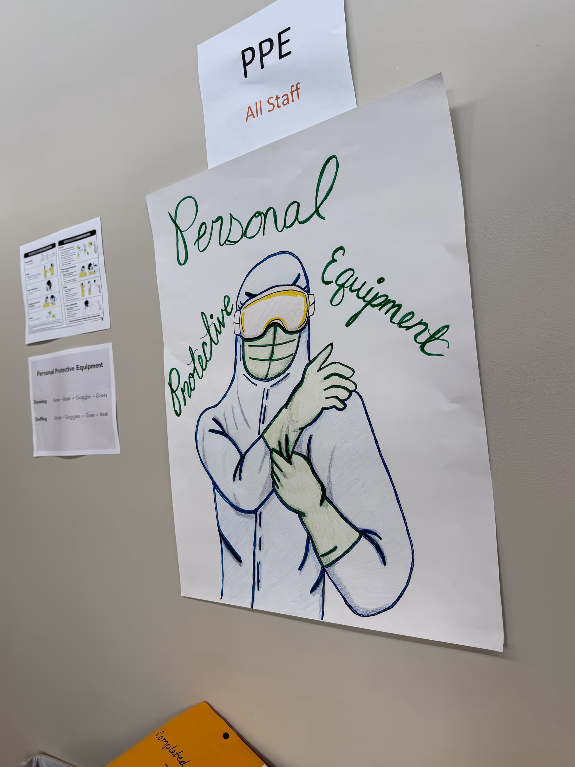 Interior wall with PPE signage and a large protective equipment poster.