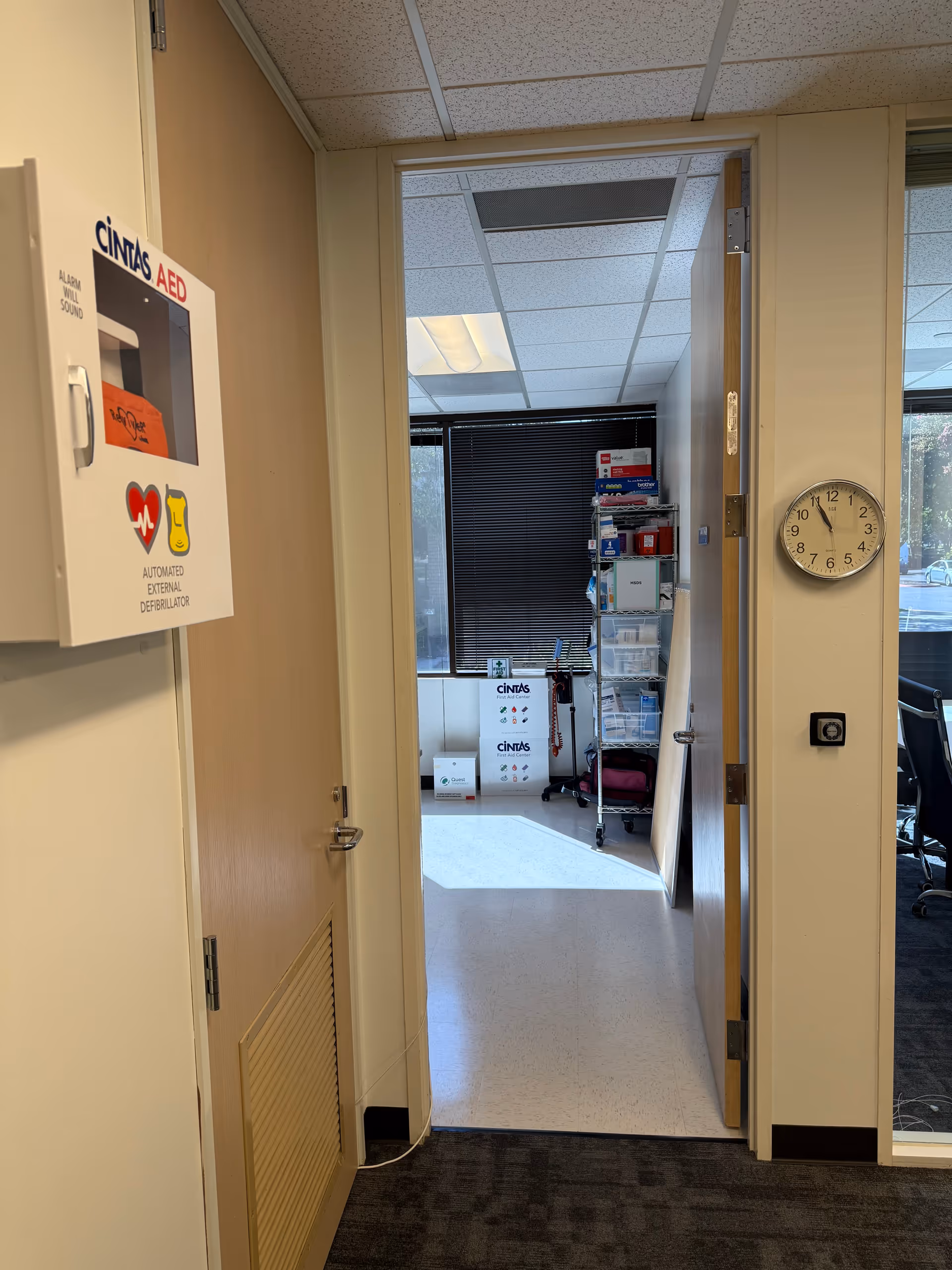 Interior hallway with an open door to a medical supply area and a wall clock.