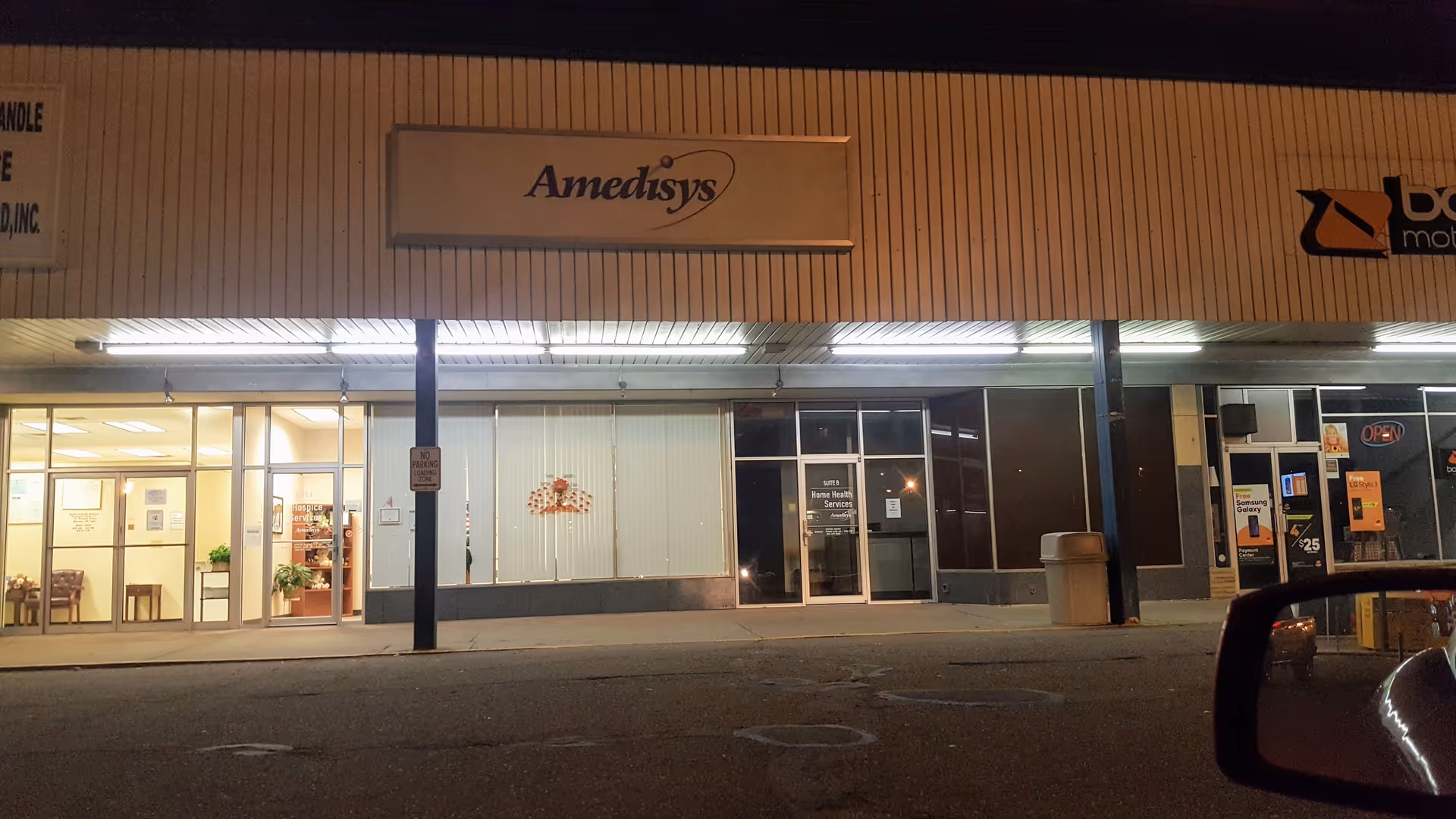 Nighttime exterior view of a storefront with an Amedisys Hospice Care sign.