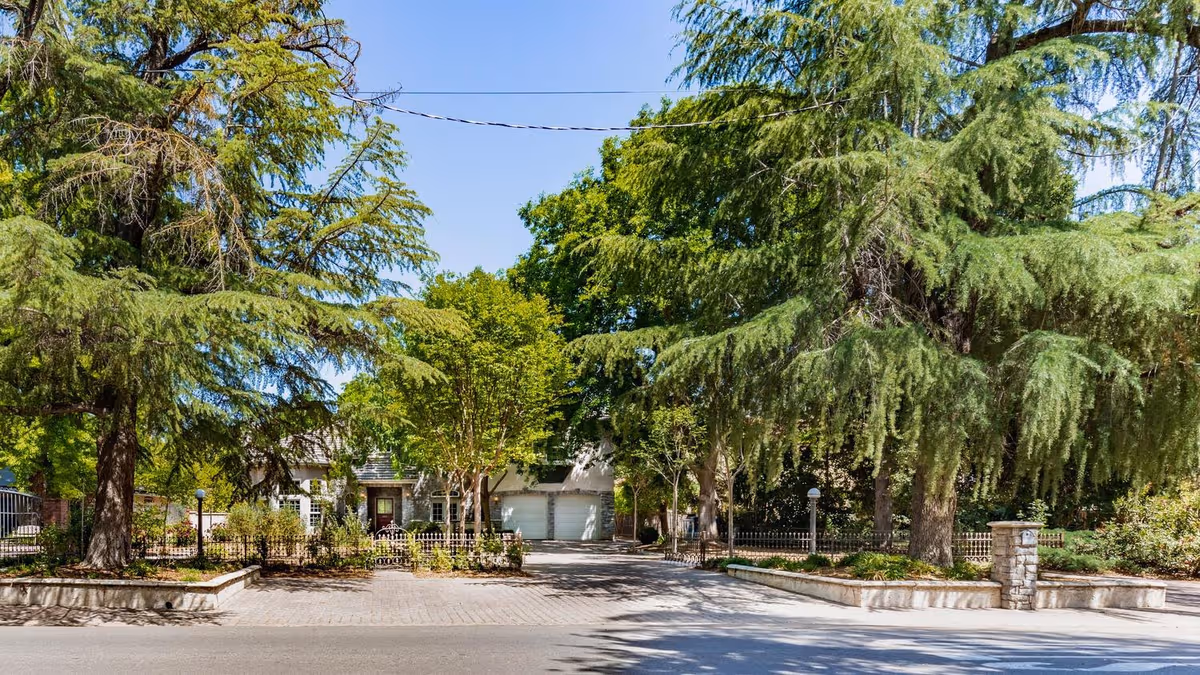 Facade of Nazareth House of Fresno with a driveway, trees, and a gated entrance.