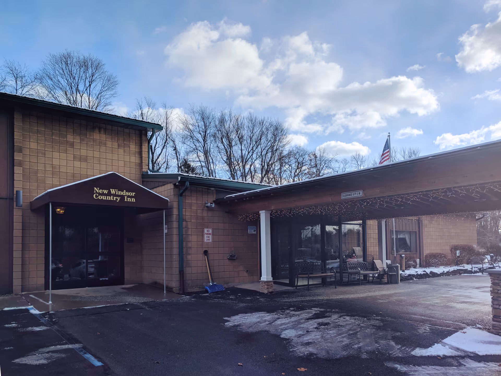 Exterior view of New Windsor Country Inn entrance with canopy and outdoor seating.