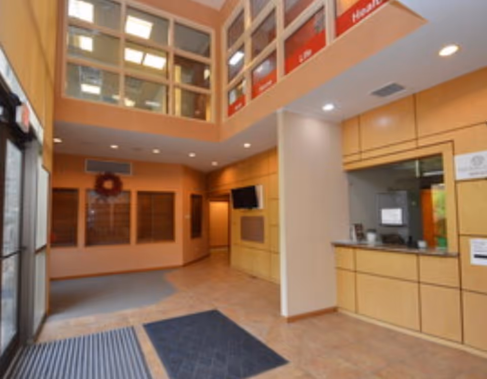 Interior lobby of a senior living facility with a reception desk and warm wood walls.