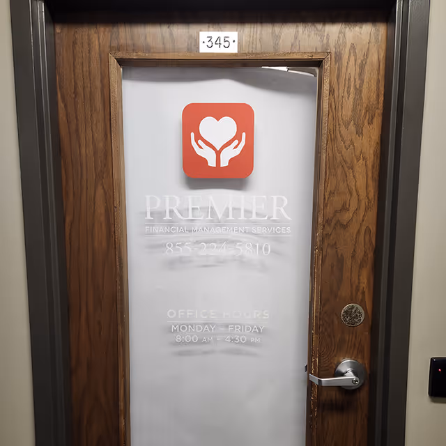 Wooden-framed interior door with frosted glass sign for Premier Financial Management Services.