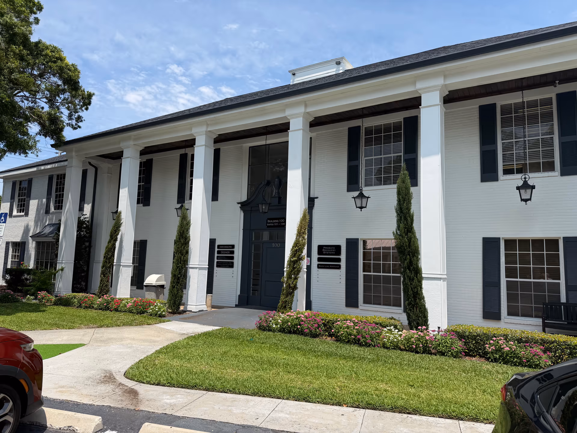 White senior living facility exterior with tall columns and manicured landscaping.