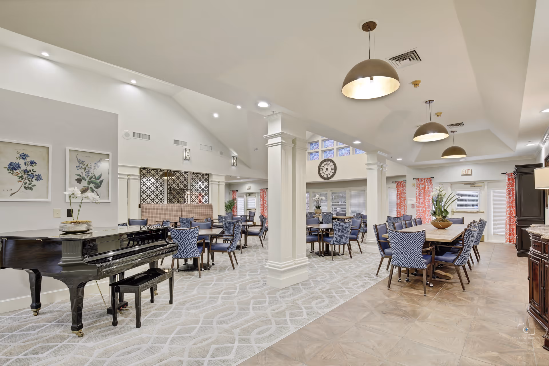 Spacious senior living common area with a grand piano and many blue upholstered chairs.