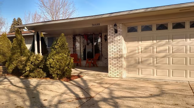 Front exterior of a Hearthstone Communities building with brick facade, porch chairs, and a garage.