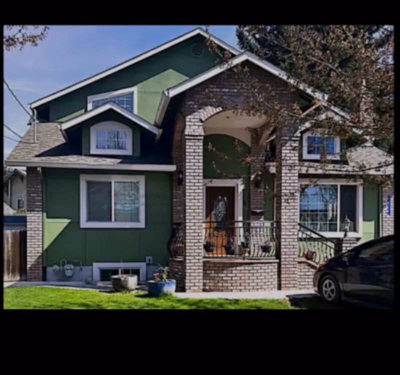 Front view of a green-brick house with a brick porch and a parked car.
