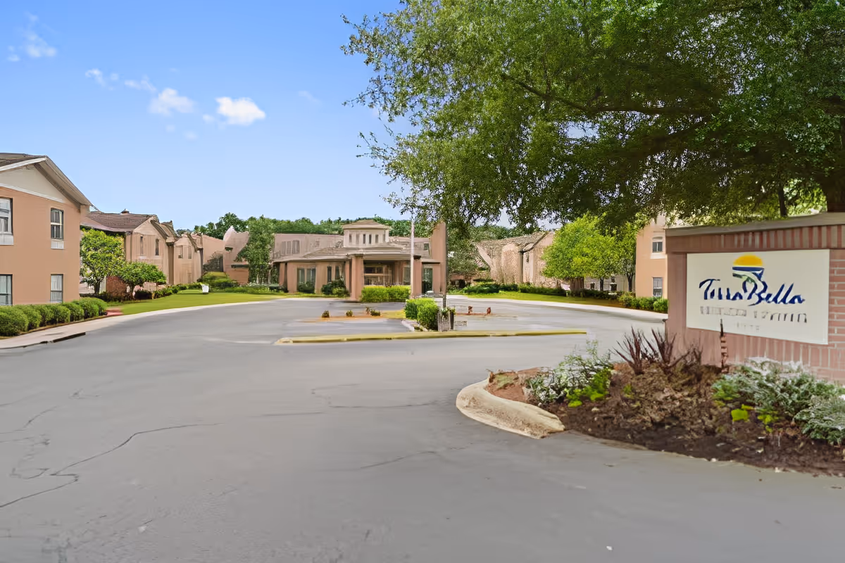 Driveway and front entrance of a senior living complex with a TerraBella sign, landscaped beds, and multi-story buildings.