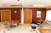 Therapy room in a senior facility with a bed, curtain divider, and exercise equipment.