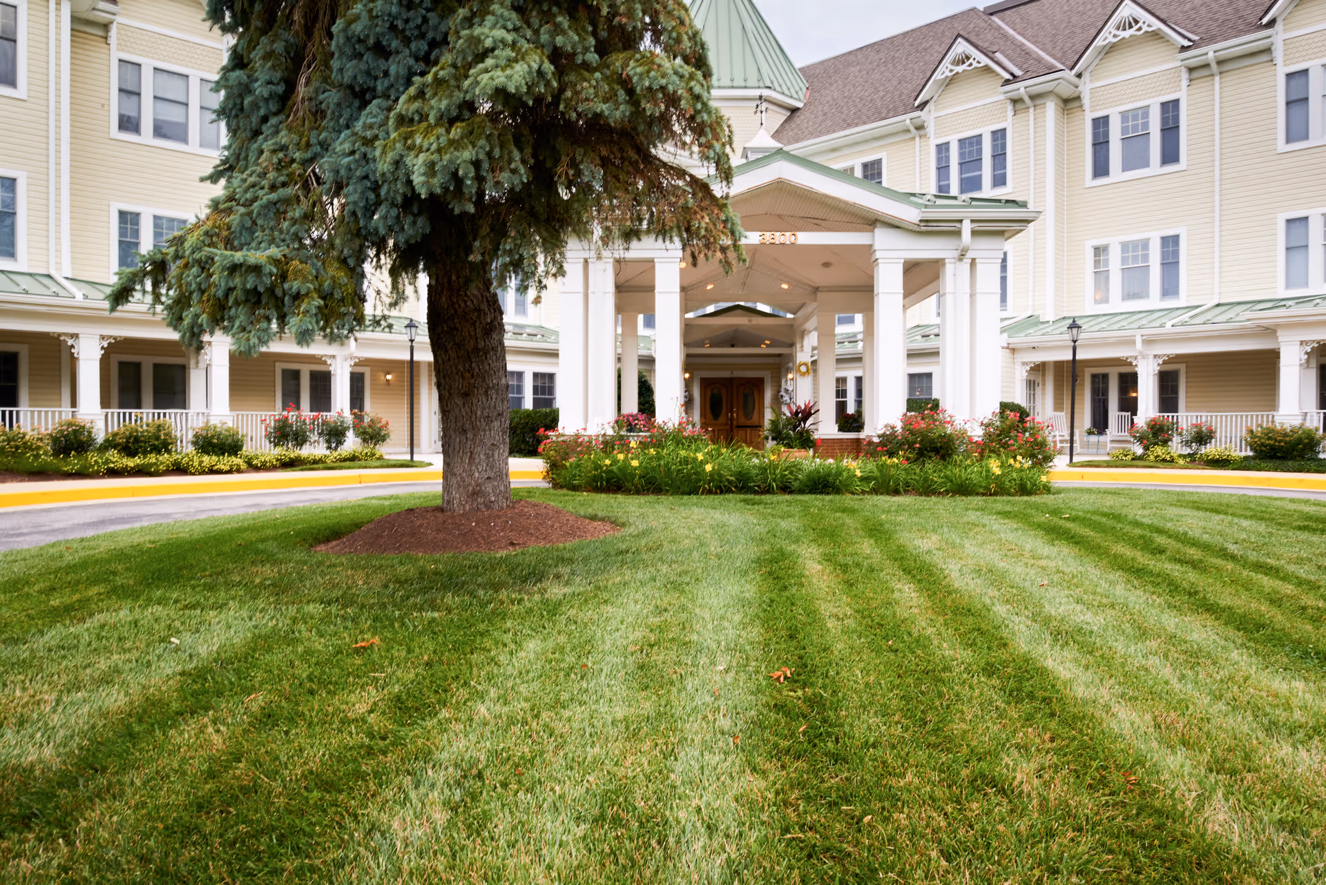 Sunrise of Pikesville building exterior with front entrance, columns, and manicured lawn.