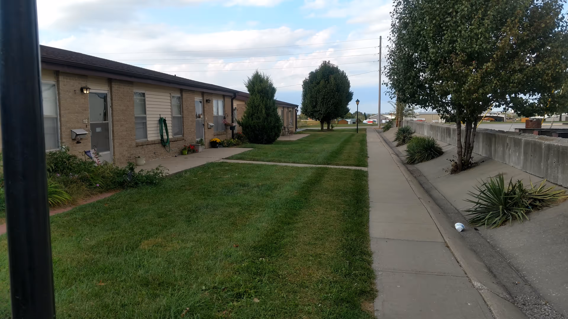 Exterior view of Lutheran Good Shepherd Home with a grassy lawn and walkway along the building.