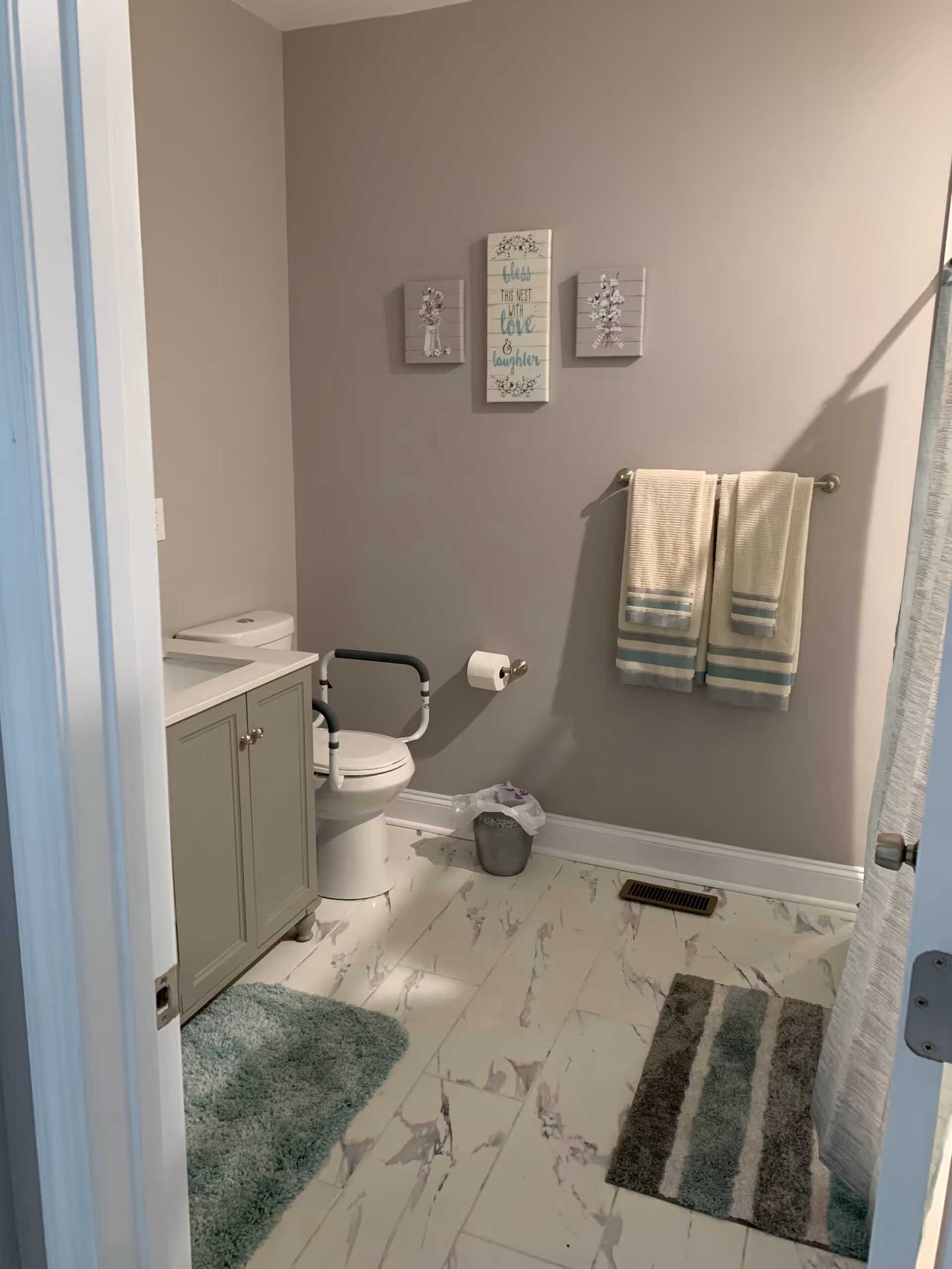 Accessible bathroom with toilet, sink vanity, grab bar, towels, and wall art.