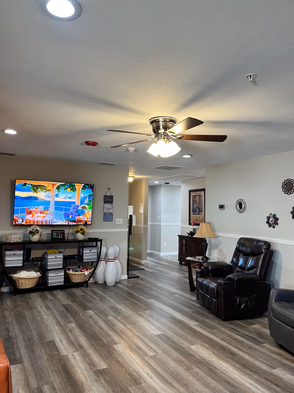 Indoor common lounge with ceiling fan, leather recliner, TV, and decor.